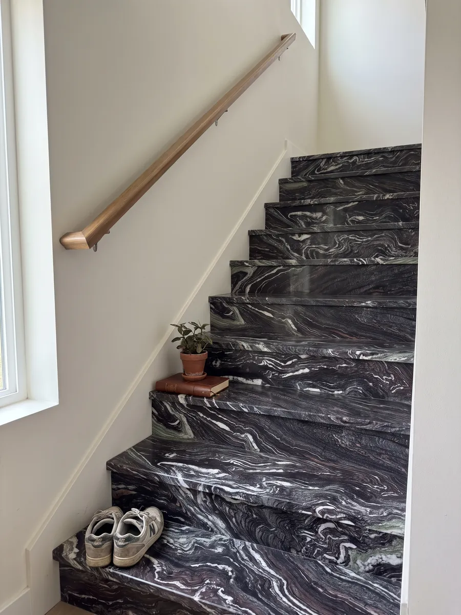 Interior staircase with Cipollino Ondulato marble treads and a handrail: deep purple background with strongly wavy, folded white veins