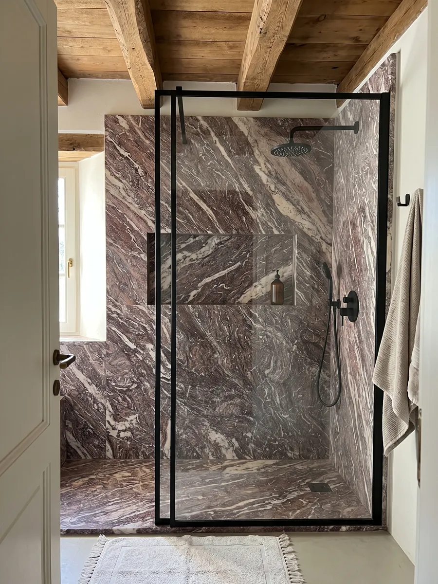Shower clad in full Cipollino Viola marble slabs with a recessed niche: reddish violet with dense fine folds and some white veins