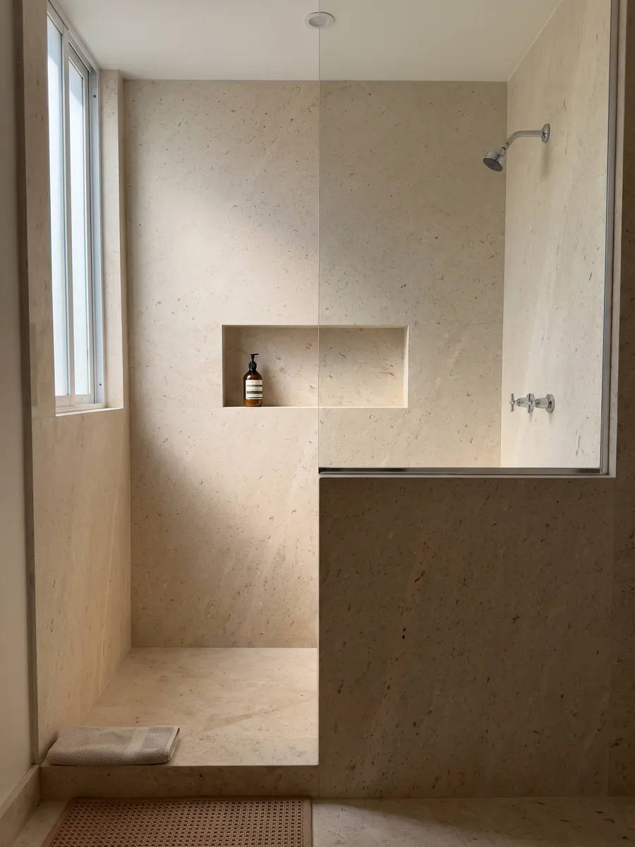 Shower clad in full Fior di Crema marble slabs with a recessed niche: a very even cream surface, fine grained, with no visible veins