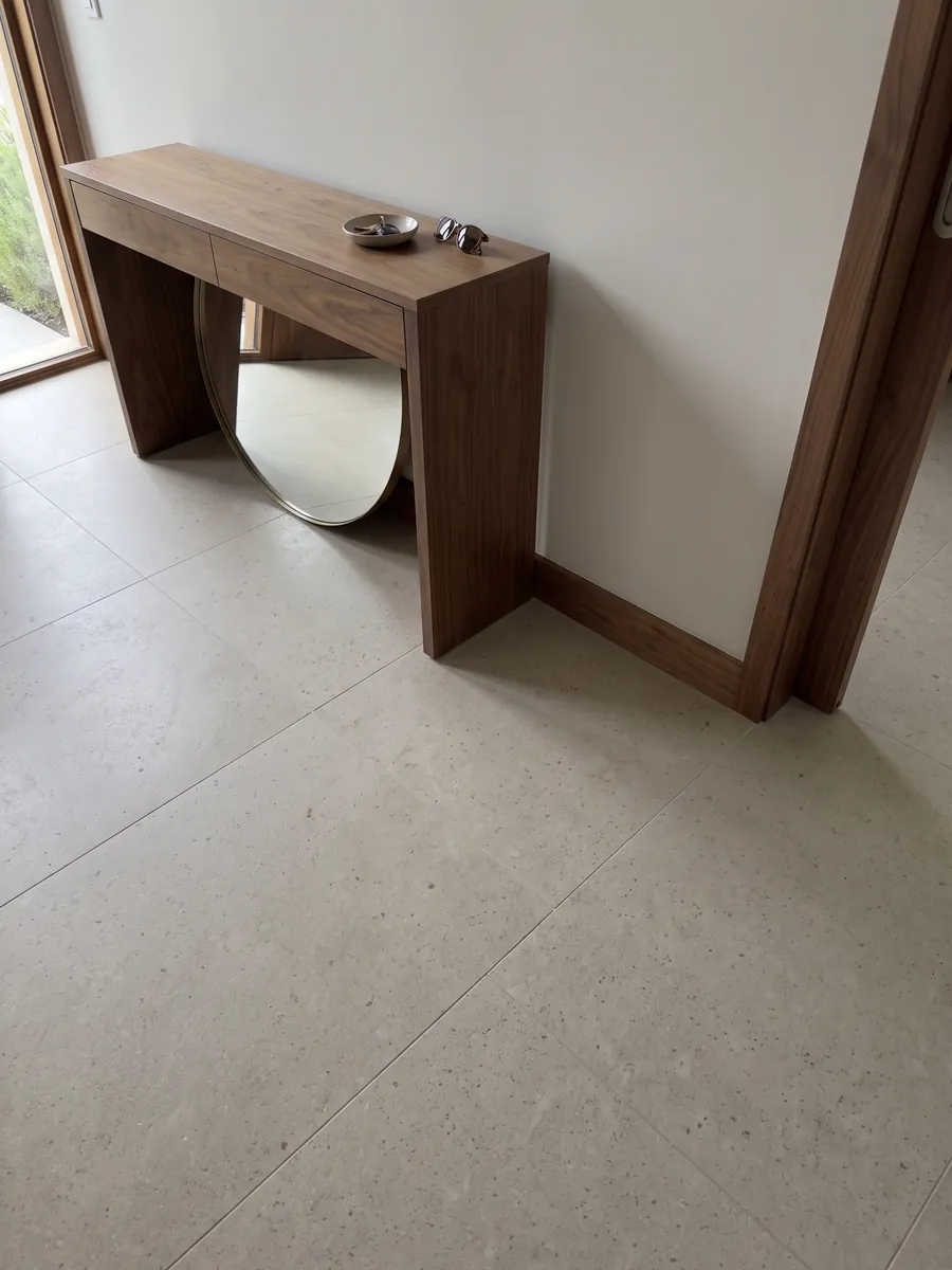 Entryway floor in large slabs of Gascogne Beige marble with natural light: a nearly smooth grayish beige with barely visible dark specks