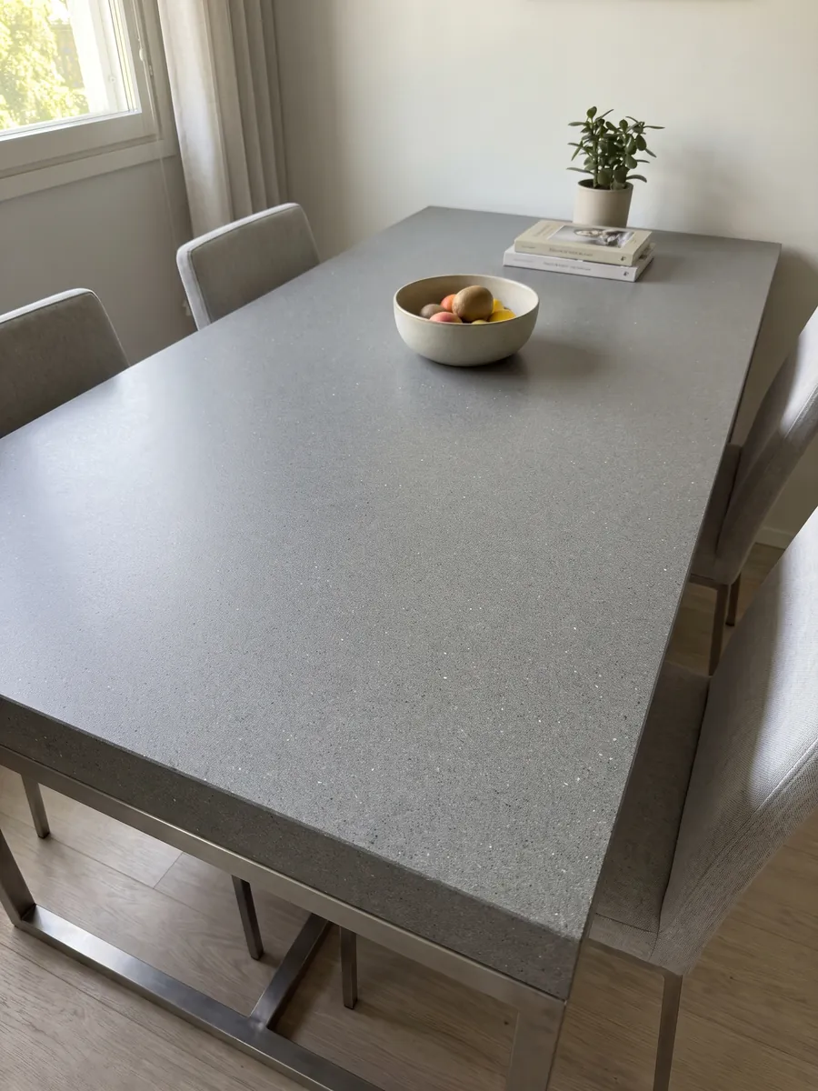 Dining table with a Grigio Aitos marble top on a steel base: medium gray, fine grained, evenly speckled, no veins