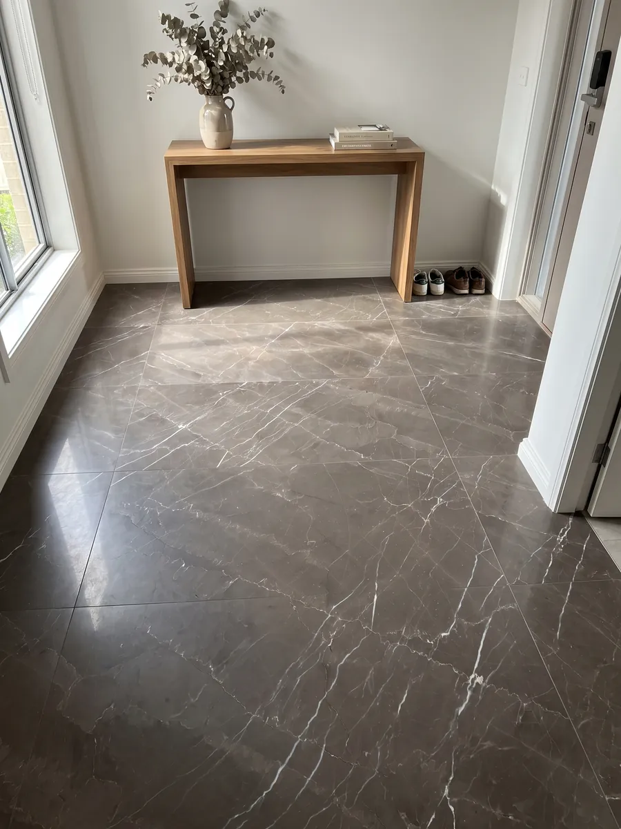 Entryway floor in large Grigio Amani marble slabs with natural light: dark taupe background crossed by fine white diagonal veins