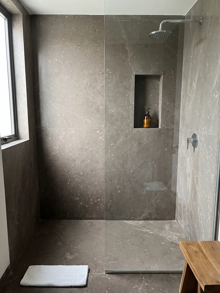 Shower clad in full Grigio Antracite marble slabs with a recessed niche: taupe gray with small flecks and barely a fine white vein