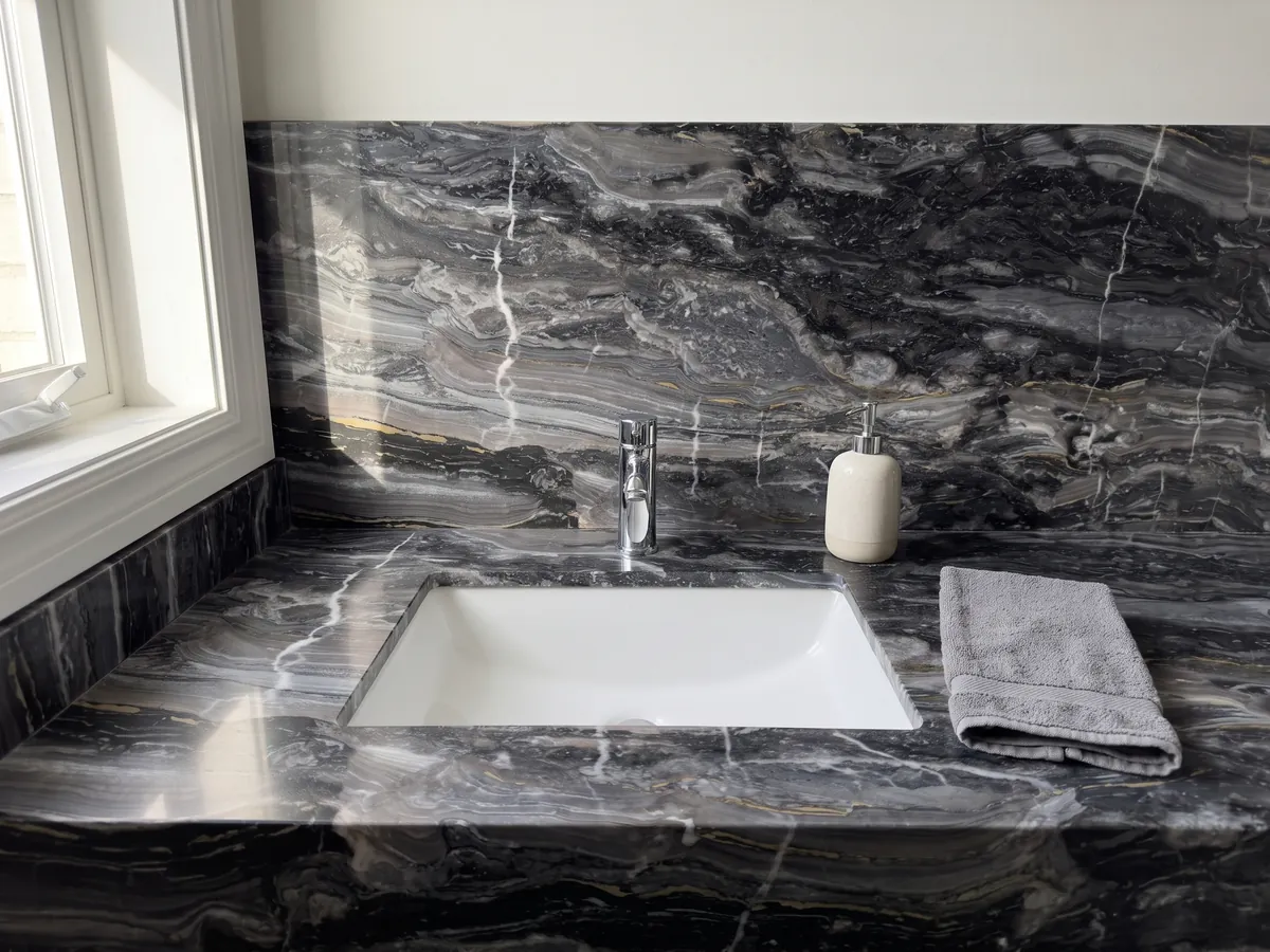 Vanity top and bathroom wall in gray Arabescato Grigio Orobico marble: anthracite gray with horizontal waves and a few fine white veins cutting across it vertically