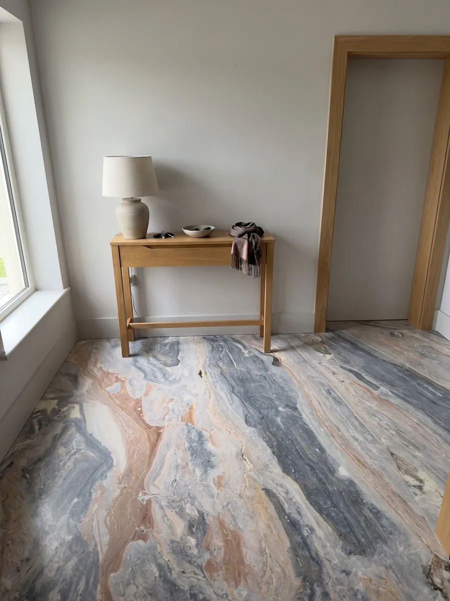 Entryway floor in large slabs of gray Arabescato Orobico Grigiorosa marble with natural light: mixed blue-gray and salmon pink waves running diagonally across the whole slab
