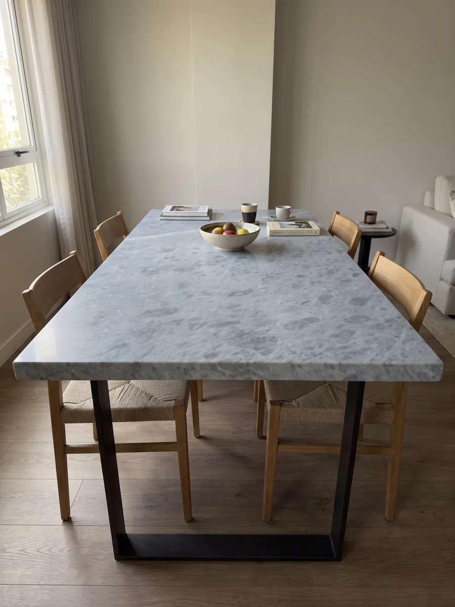 Dining table with a gray Bardiglio Imperiale marble top on a steel base: even blue-gray with round spots slightly darker