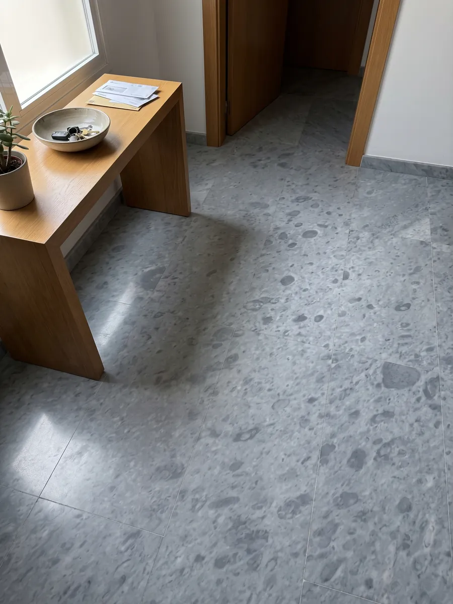 Entryway floor in large gray Bardiglio Imperiale marble slabs with natural light: even blue-gray with round spots slightly darker