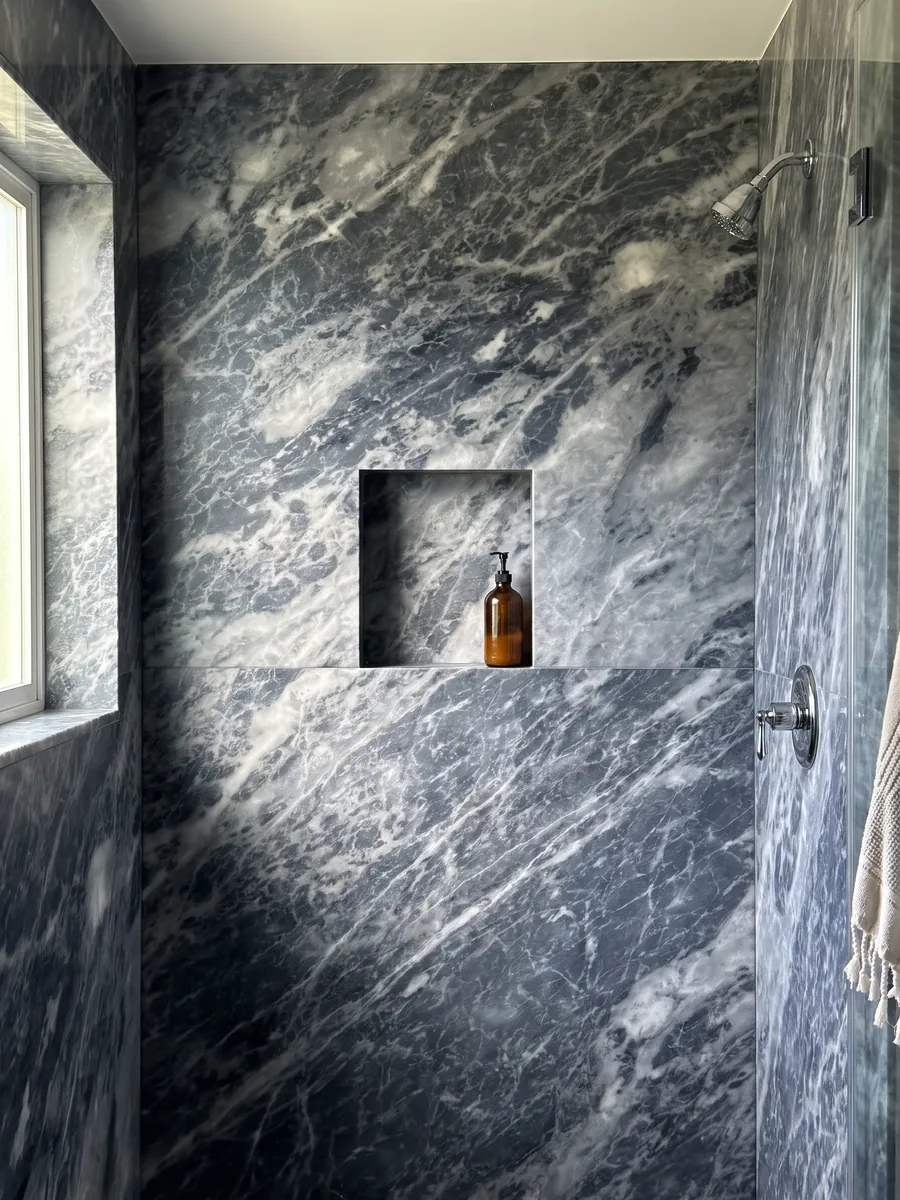 Shower clad in full gray Bardiglio Nuvolato marble slabs with a recessed niche: dark blue-gray with diffuse whitish clouds and veins in diagonal
