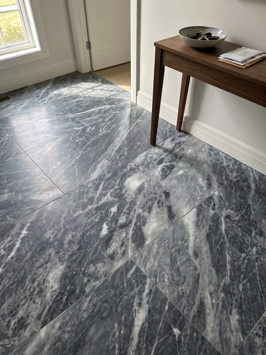 Entryway floor in large gray Bardiglio Nuvolato marble slabs with natural light: dark blue-gray with diffuse whitish clouds and veins in diagonal