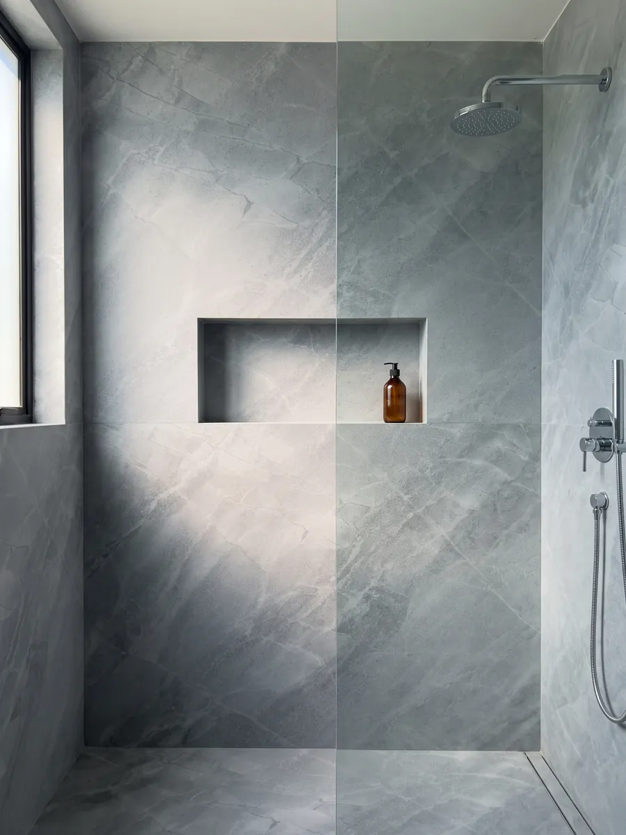 Shower clad in full slabs of gray Bleu de Savoie marble with a recessed niche: blue-gray with a fine web of light veins and lighter clouds