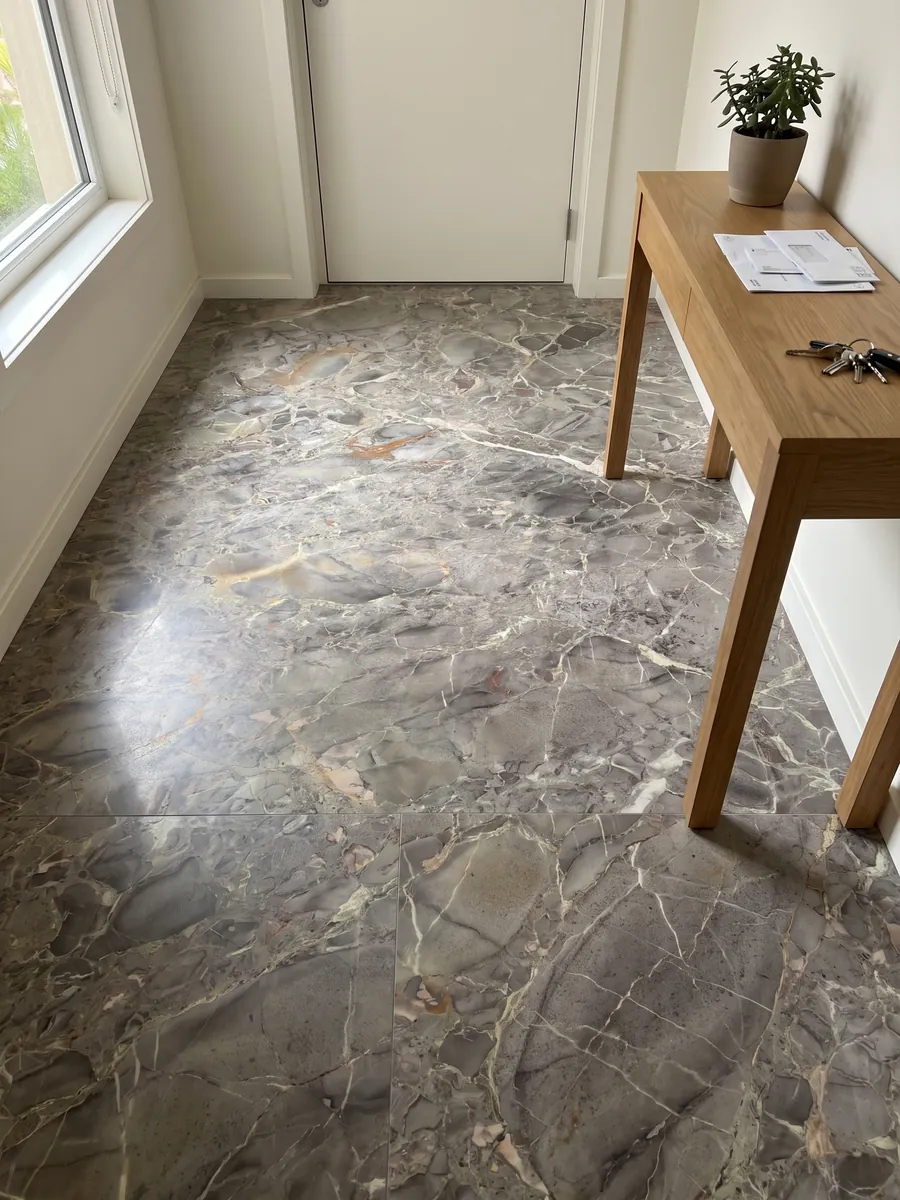 Entryway floor in large slabs of gray Breccia di Versailles marble in natural light: gray-brown with soft-edged fragments, fine light veins and ochre touches