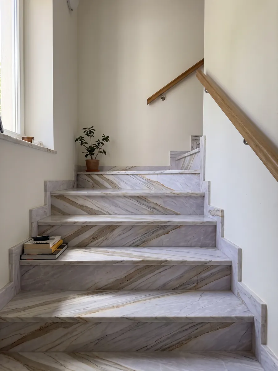 Interior staircase with gray Calacatta Supreme marble treads and a handrail: light lavender gray with diagonal beige bands and fine ocher lines