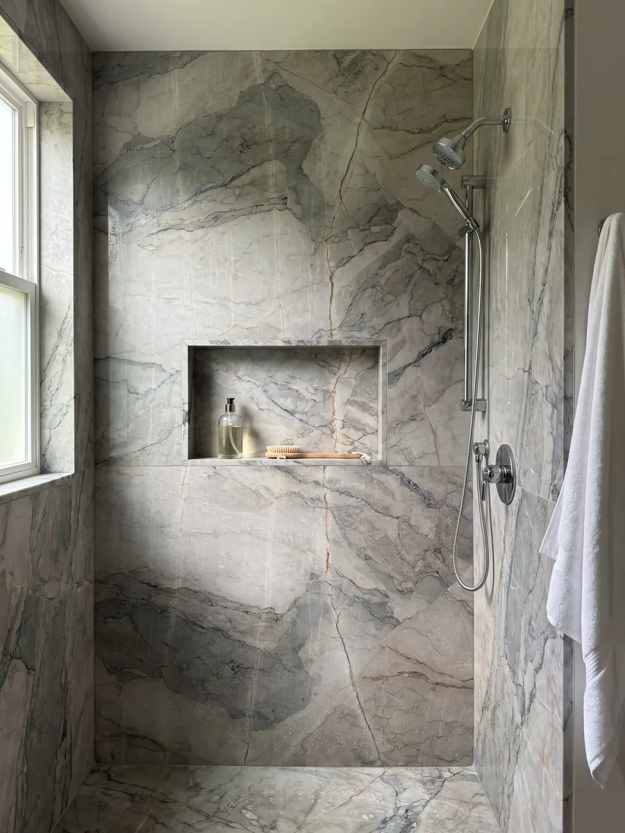 Shower clad in full slabs of gray Camouflage marble with a recessed niche: lavender-gray and blue-gray fragments with fine veins in a mosaic pattern