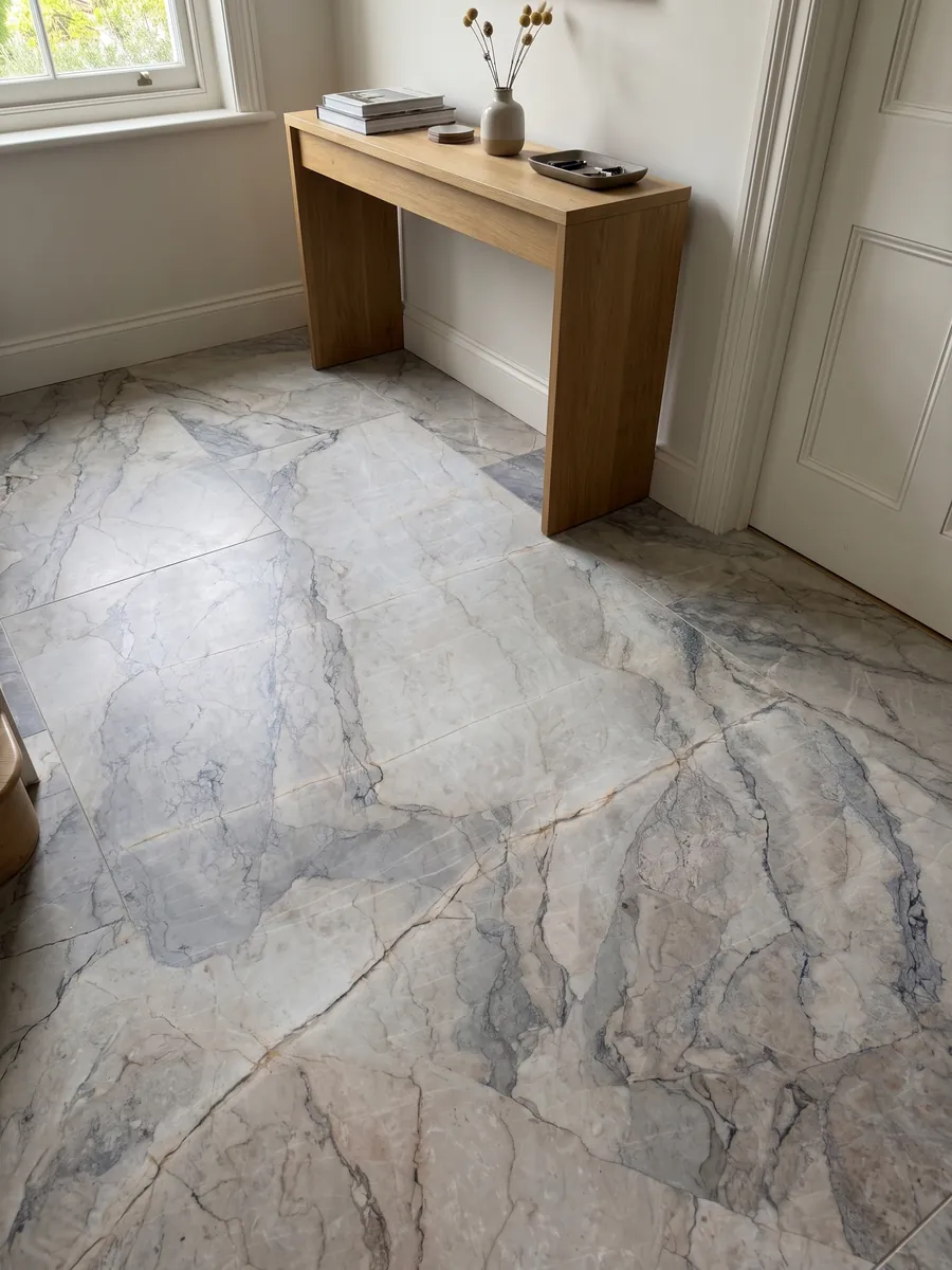 Entryway floor in large slabs of gray Camouflage marble with natural light: lavender-gray and blue-gray fragments with fine veins in a mosaic pattern
