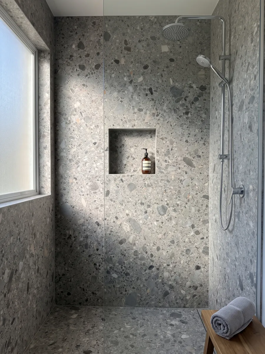 Shower clad in full slabs of gray Ceppo marble with a recessed niche: gray matrix with gray, beige and black pebbles of various sizes