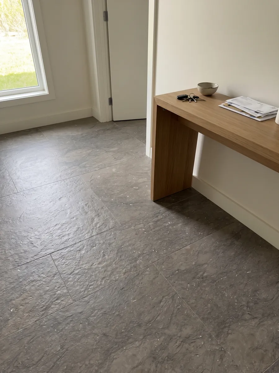Entryway floor in large slabs of gray Ebano marble with natural light: an even gray-brown with small sparkling light specks