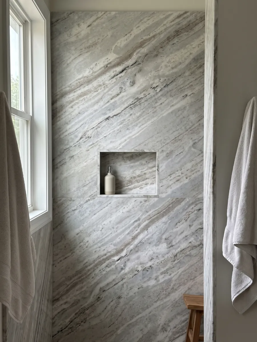 Shower clad in full slabs of gray Fantasy Brown marble with a recessed niche: elongated white and gray clouds with some dark diagonal streaks