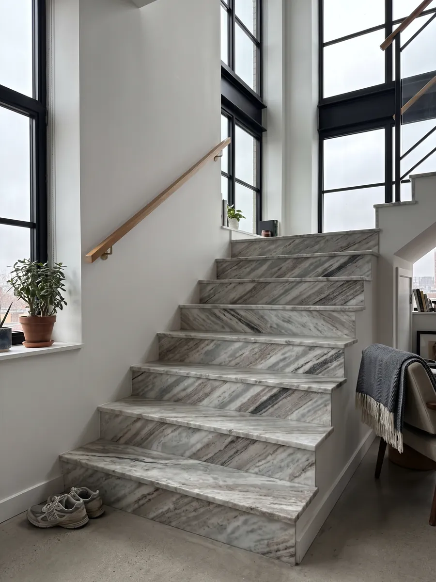 Interior staircase with gray Fantasy Brown marble steps and a handrail: elongated white and gray clouds with some dark diagonal streaks