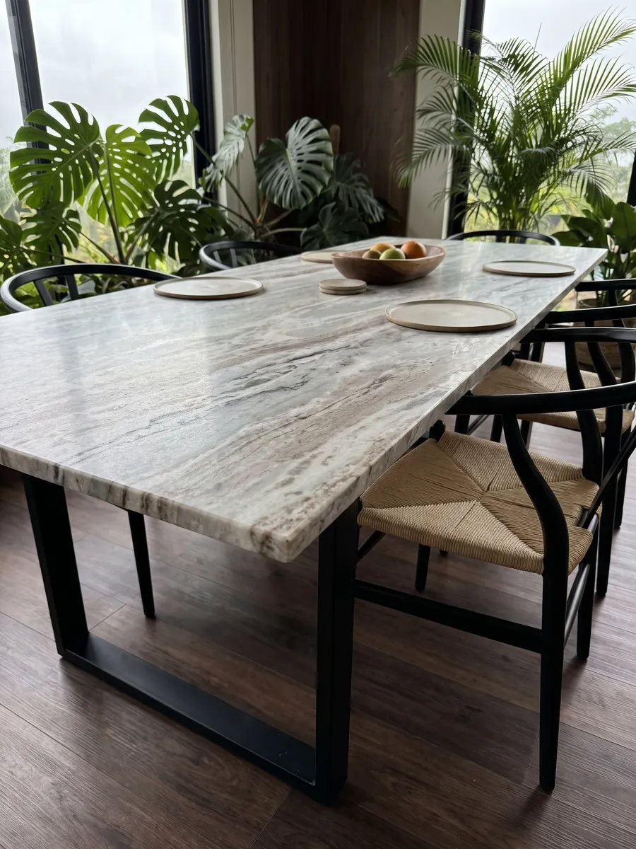 Dining table with a gray Fantasy Brown marble top on a steel base: elongated white and gray clouds with some dark diagonal streaks