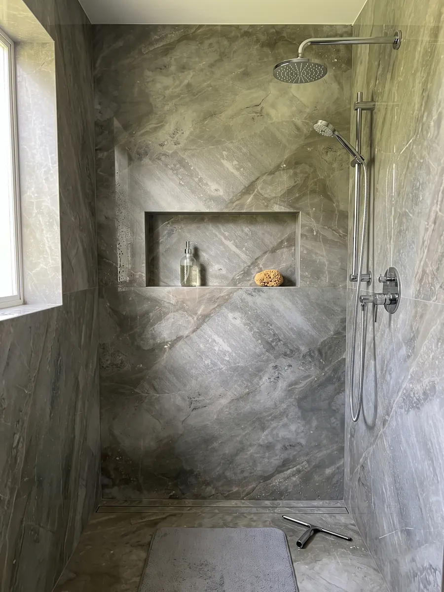 Shower clad in full slabs of gray Fior di Bosco marble with a recessed niche: muted greenish gray with tonal clouds and nearly invisible fine veins