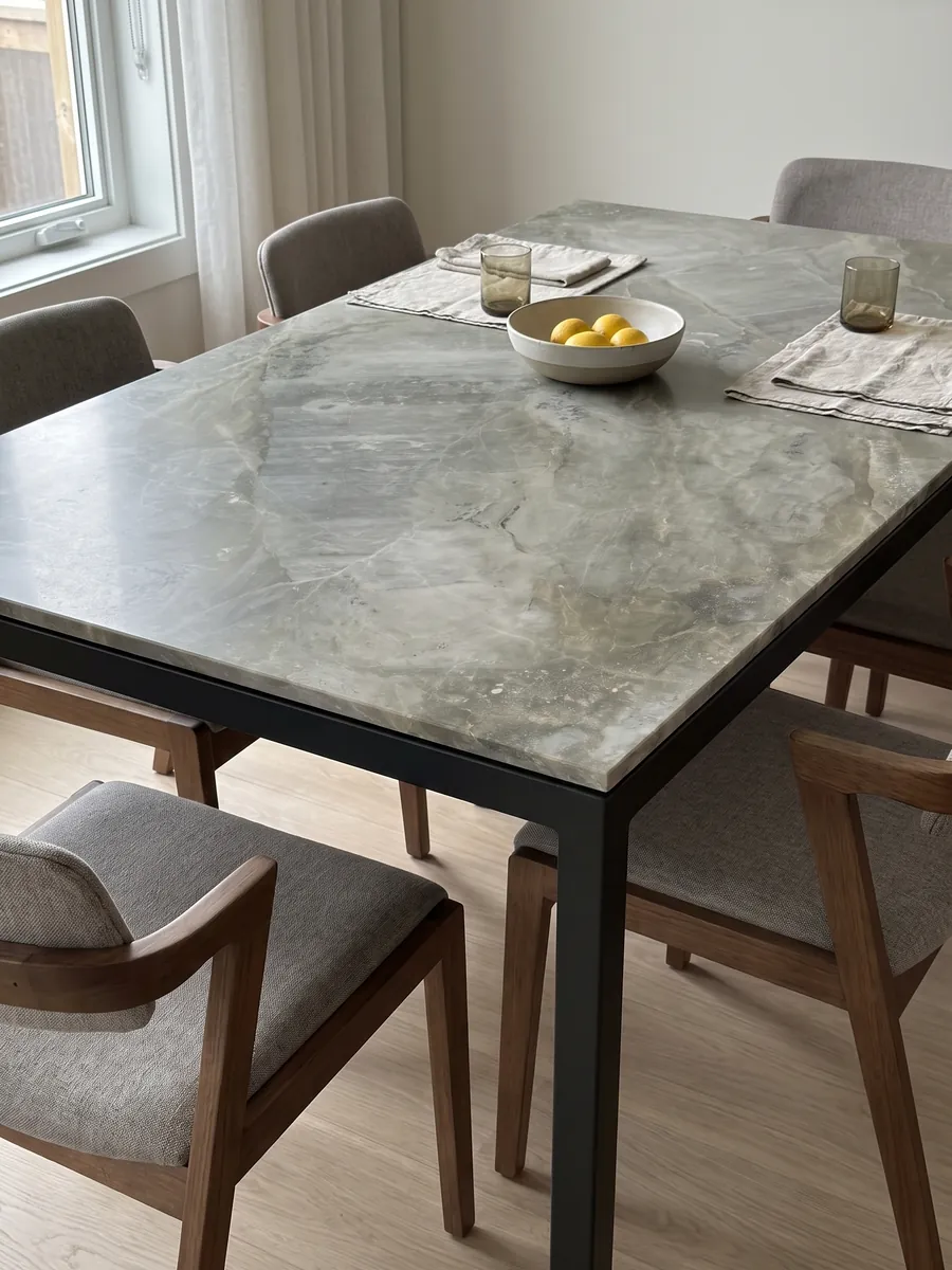 Dining table with a gray Fior di Bosco marble top on a steel base: muted greenish gray with tonal clouds and nearly invisible fine veins