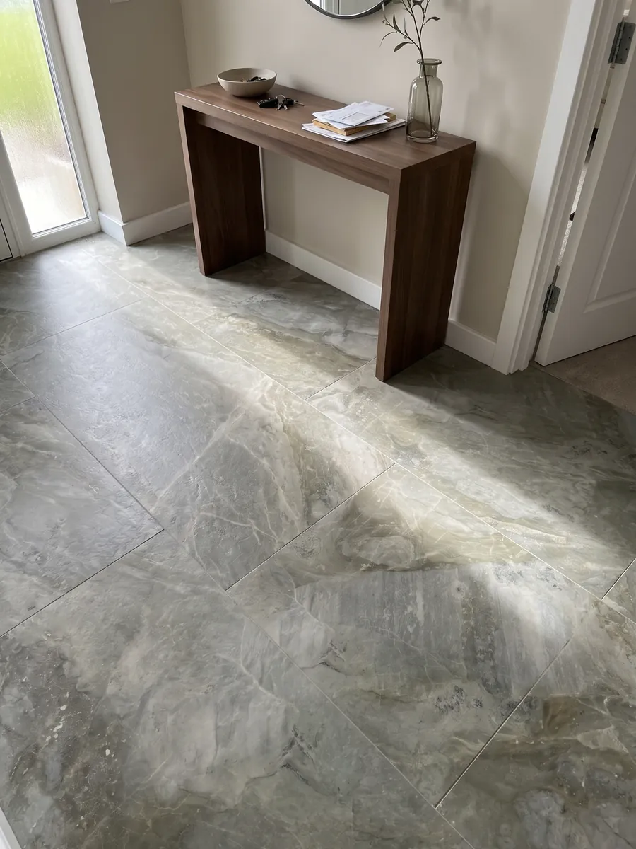 Entryway floor in large slabs of gray Fior di Bosco marble with natural light: muted greenish gray with tonal clouds and nearly invisible fine veins