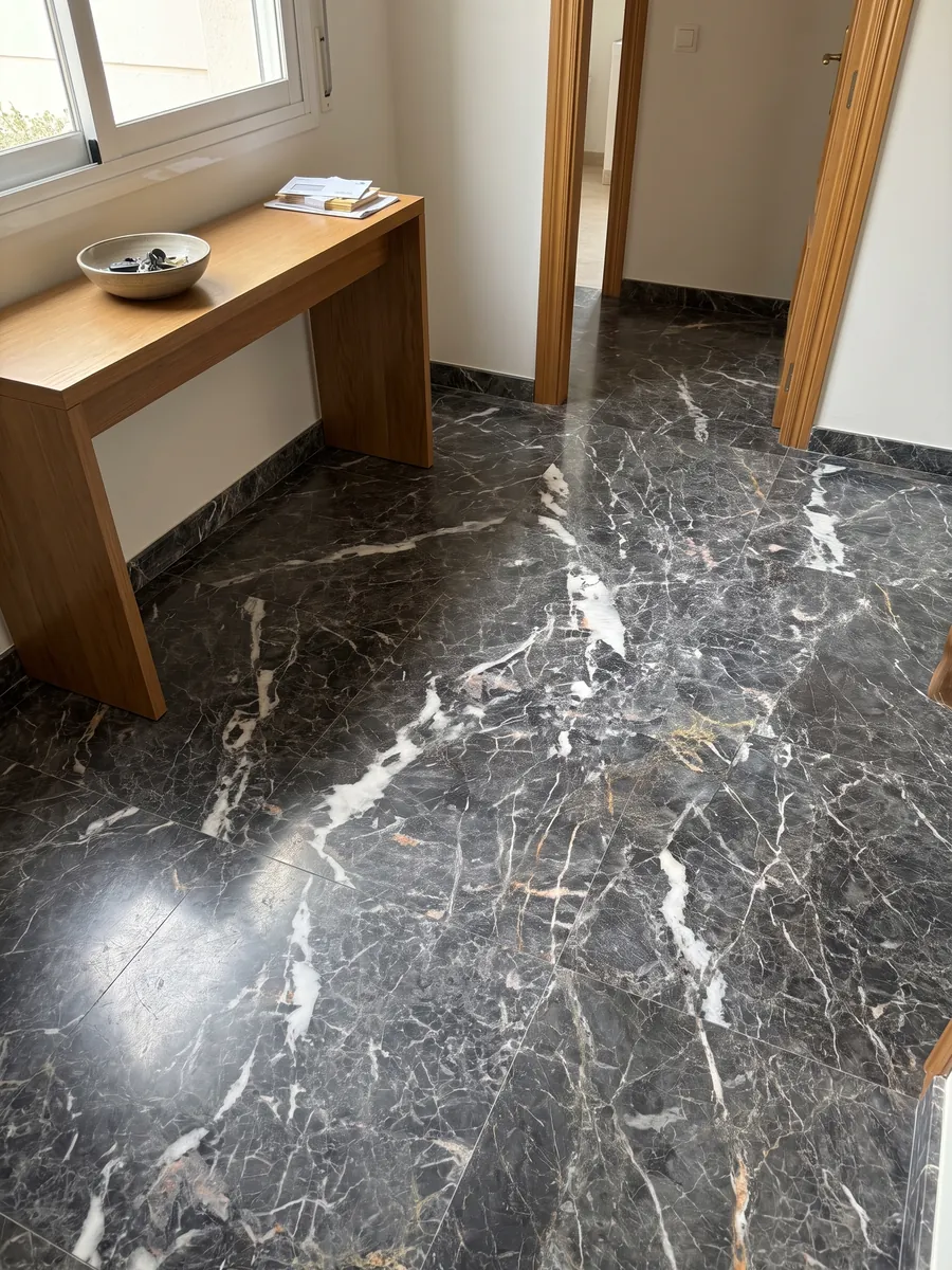 Entryway floor in large slabs of Grey Saint Laurent gray marble with natural light: dark gray with elongated white patches and a fine network of light and golden veins