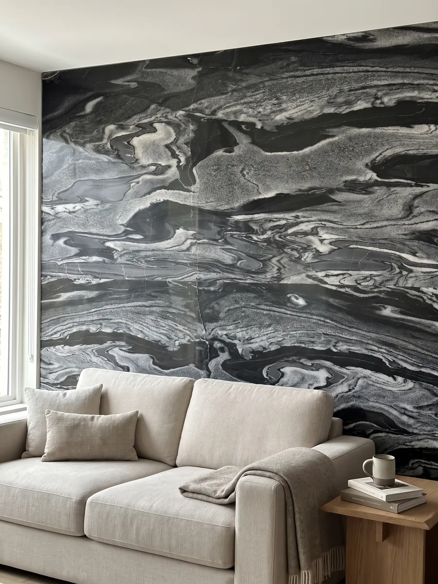 Living room wall clad in bookmatched Grigio Imperiale marble slabs behind a sofa: horizontal gray and white waves over black, like moving currents