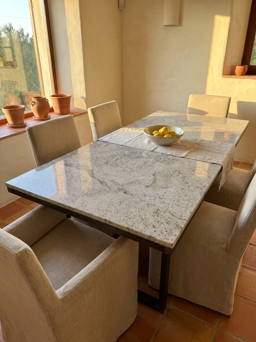 Dining table with a gray Lemon Ice marble top on a steel base: light gray speckled with dark flecks, resembling granite
