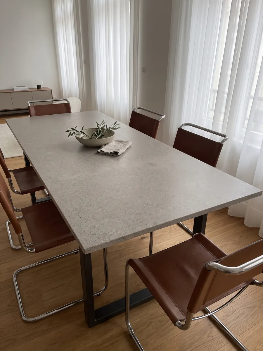 Dining table with a gray Lipica Unito marble top on a steel base: fine-grained beige gray with a very uniform look and no pattern