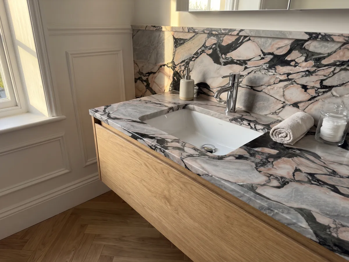 Bathroom vanity top and shower wall in gray Notre Dame marble with a white sink and chrome faucets: gray and salmon pink fragments locked in by thick black veins
