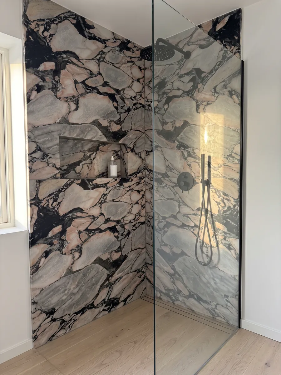 Shower clad in full gray Notre Dame marble slabs with a recessed niche: gray and salmon pink fragments enclosed by thick black veins
