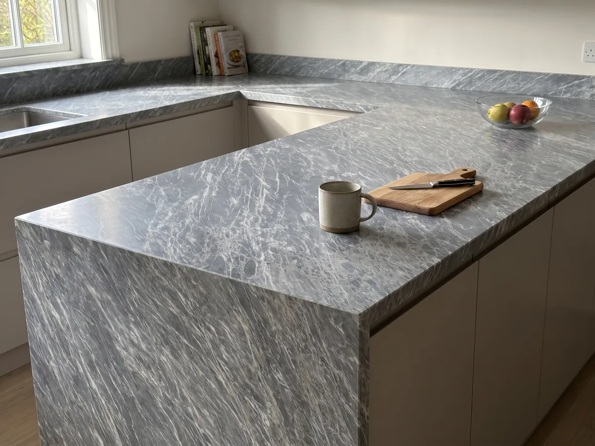 Kitchen island with a Grigio Perla marble countertop and a straight edge in a kitchen with natural light: blue-gray covered in fine parallel white strokes running diagonally