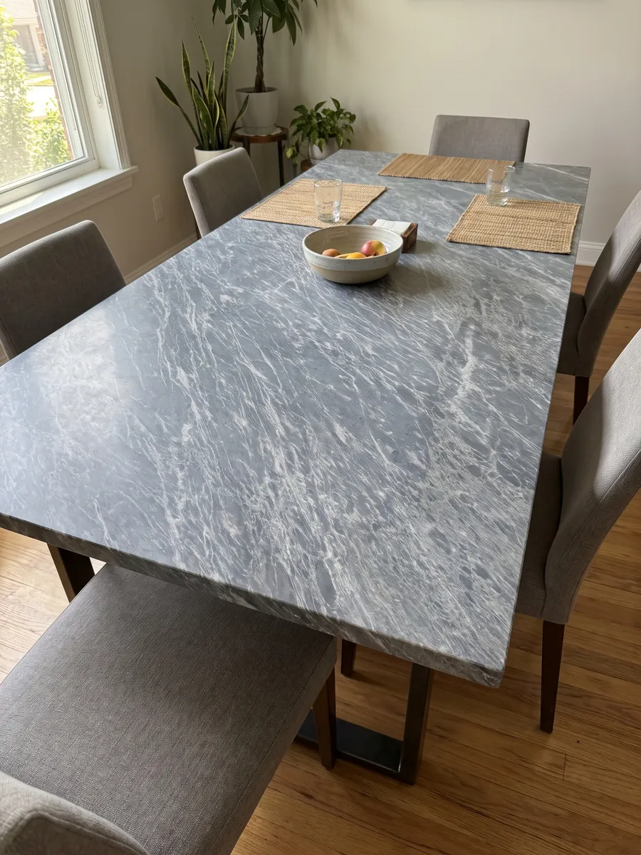 Dining table with a Grigio Perla marble top on a steel base: blue-gray covered in fine, parallel white streaks running diagonally