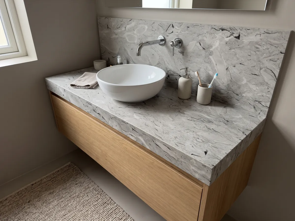Vanity top and bathroom wall in gray Repen marble with a white sink and chrome fixtures: light gray with curved black fossil marks and horizontal clouds