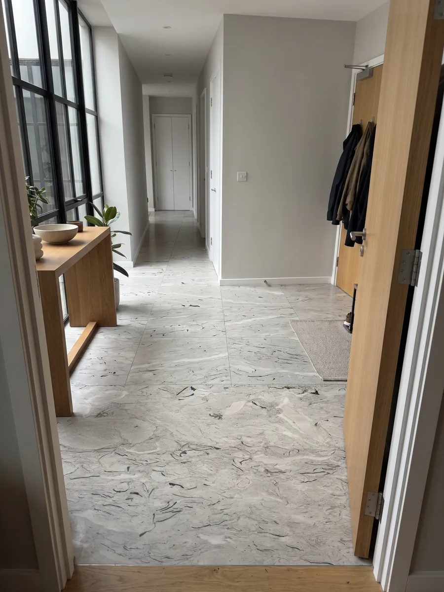 Entryway floor in large slabs of gray Repen marble with natural light: light gray with curved black fossil marks and horizontal clouds