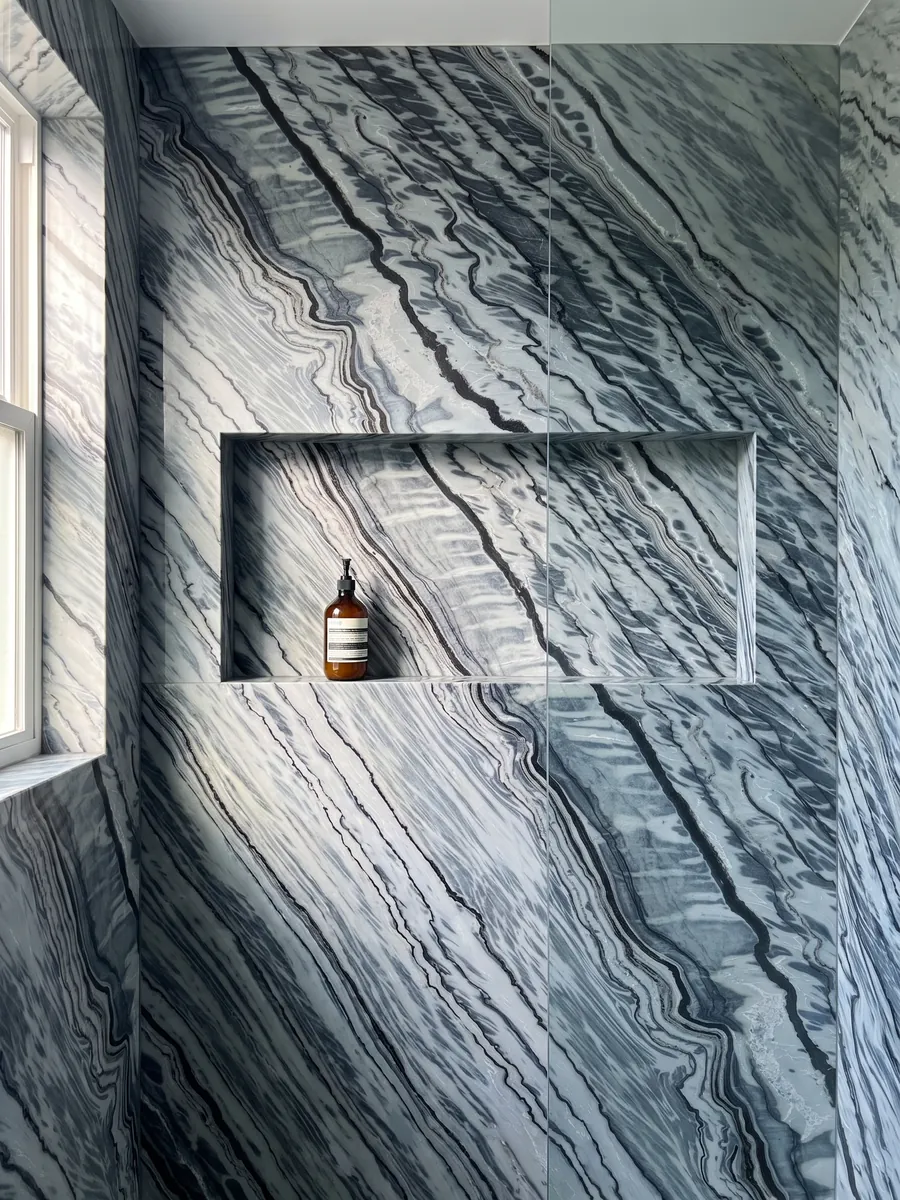 Shower clad in full Silver Stream gray marble slabs with a recessed niche: black and bluish gray wavy bands running in diagonal