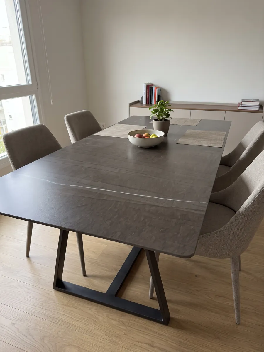 Dining table with a Grigio Tao marble top on a steel base: dark brown with faint vertical lines and a single fine white vein