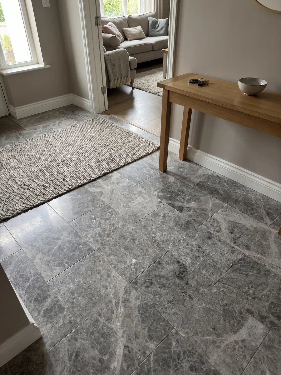 Entryway floor in large slabs of Tundra gray marble with natural light: medium gray with darker clouds and a fine speckling of light dots