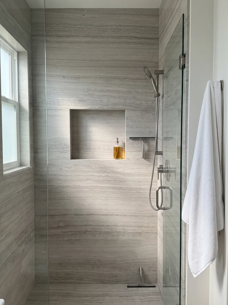 Shower clad in full slabs of gray White Wood marble with a recessed niche: light gray with fine horizontal lines that imitate wood grain