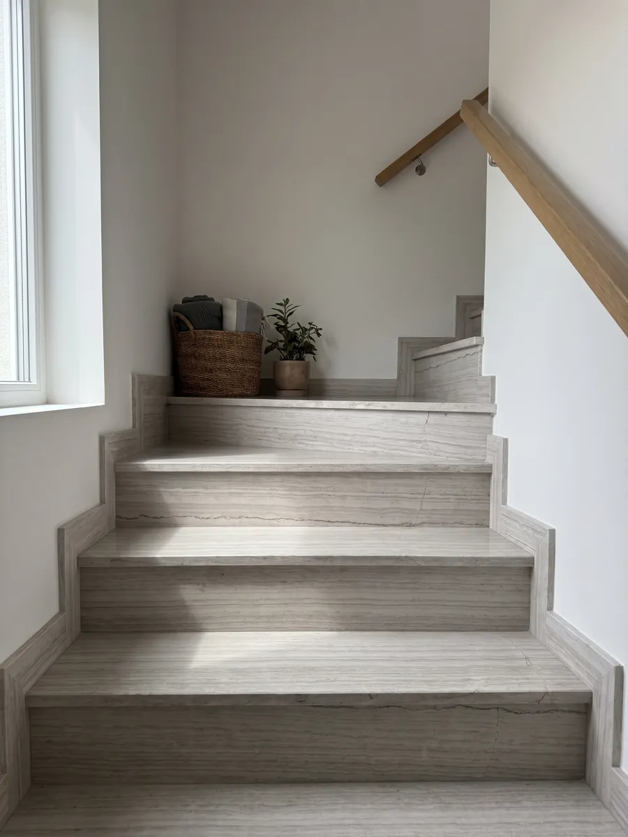 Interior staircase with gray White Wood marble treads and a handrail: light gray with fine horizontal lines that imitate wood grain
