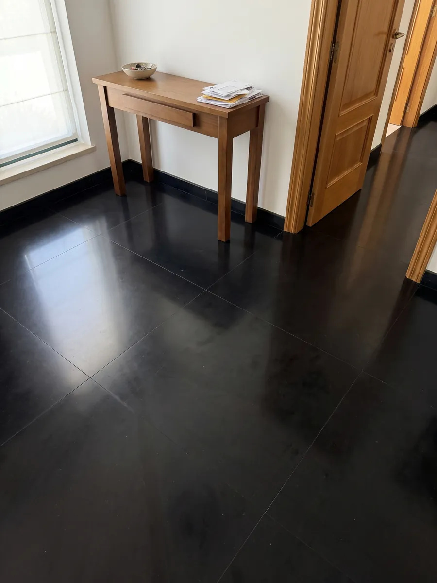 Entryway floor in large slabs of Nero Belgio marble with natural light: a completely plain, uniform black with no veins or marks