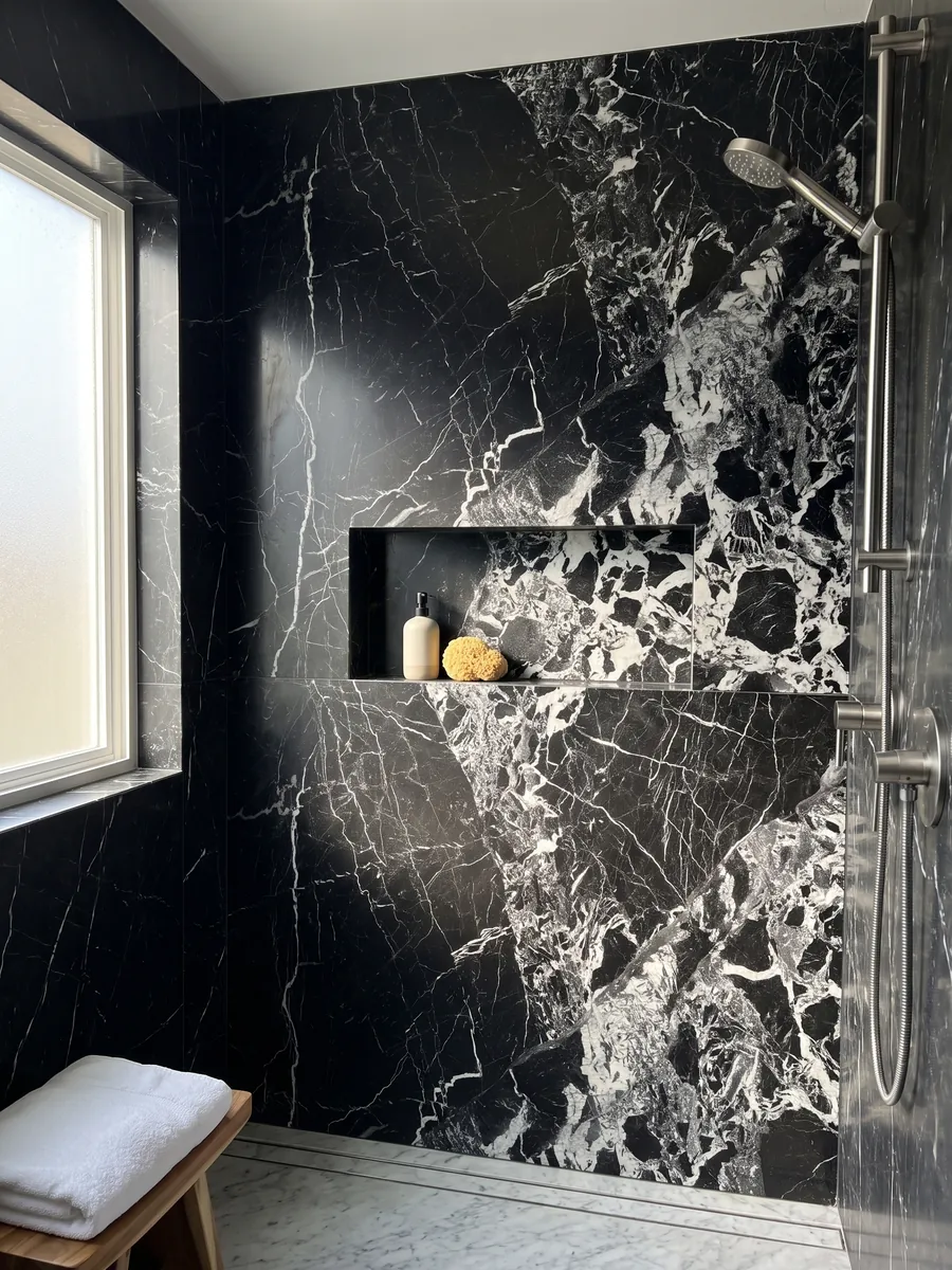 Shower clad in full black Grand Antique marble slabs with a recessed niche: intense black with an area of broken white fragments that covers one side of the slab