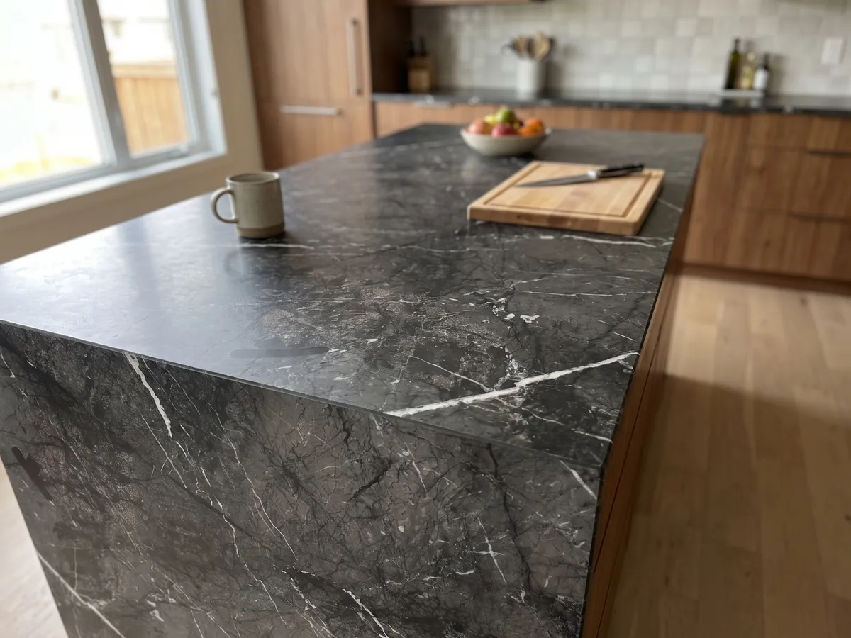 Kitchen island with a black Grigio Carnico marble countertop and a straight edge in natural light: gray-black with fine, crisp branching white veins