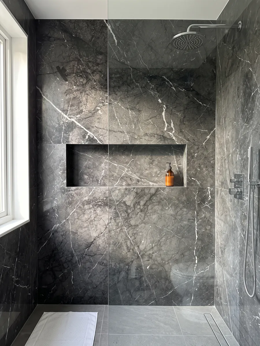Shower clad in full slabs of black Grigio Carnico marble with a recessed niche: gray-black with fine, crisp branching white veins