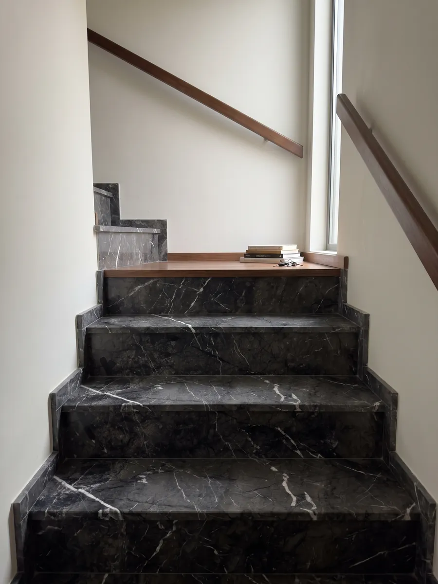 Interior staircase with black Grigio Carnico marble steps and a handrail: gray-black with fine, crisp branching white veins