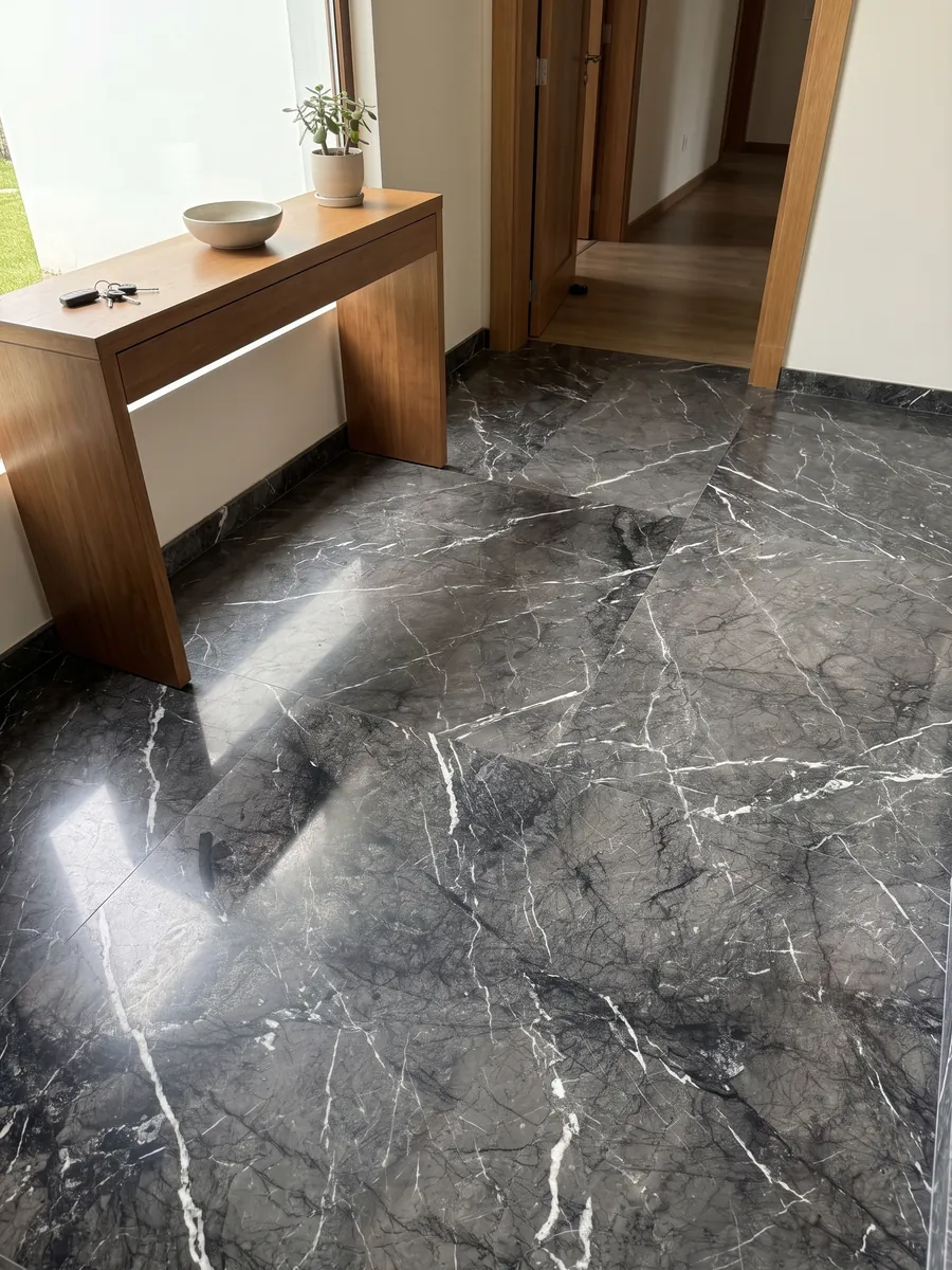 Entryway floor in large slabs of black Grigio Carnico marble with natural light: gray-black with fine, crisp branching white veins