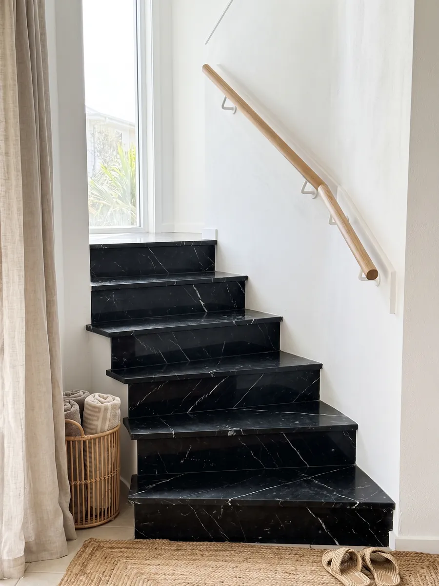 Interior staircase with black Nero Marquina marble treads and a handrail: deep black with a few fine straight white veins
