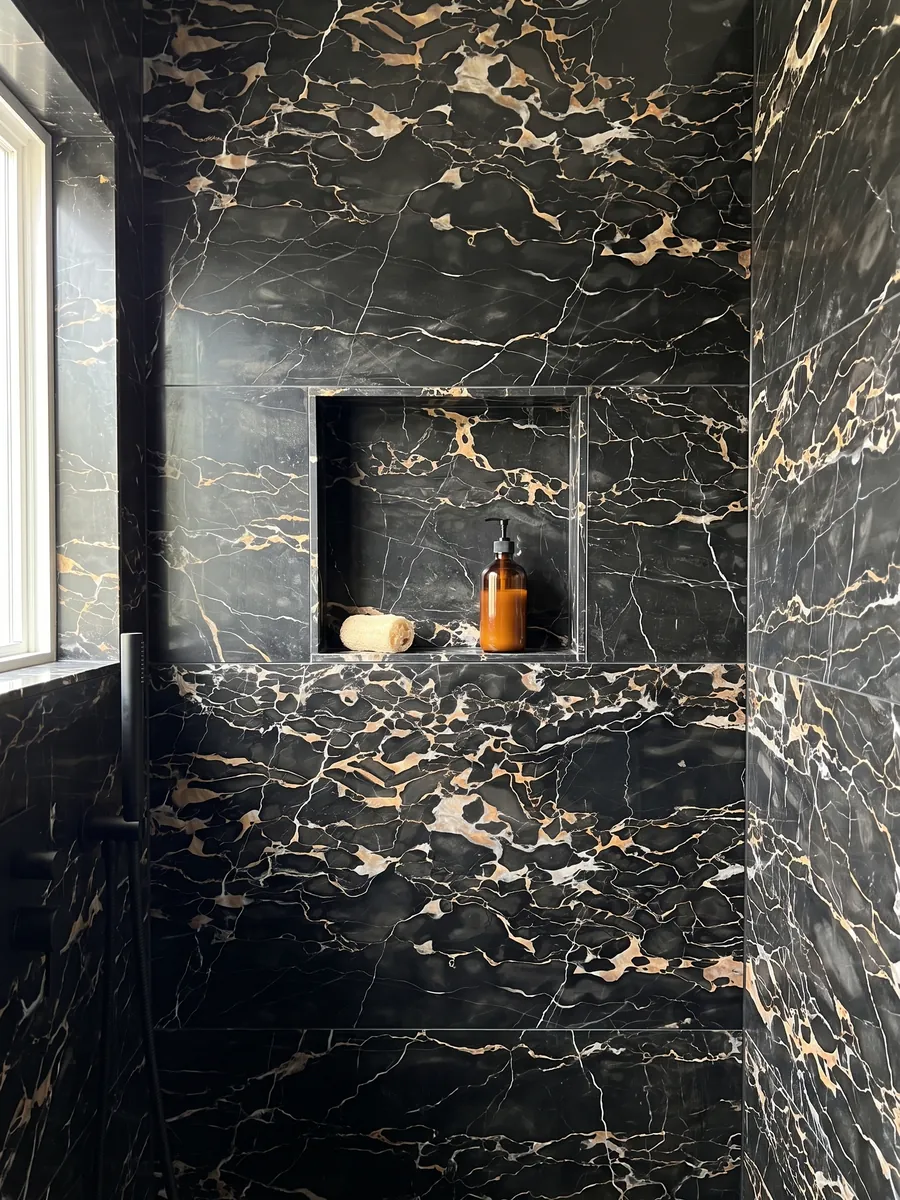 Shower clad in full slabs of black Nero Portoro marble with a recessed niche: black with a dense web of gold and white veins