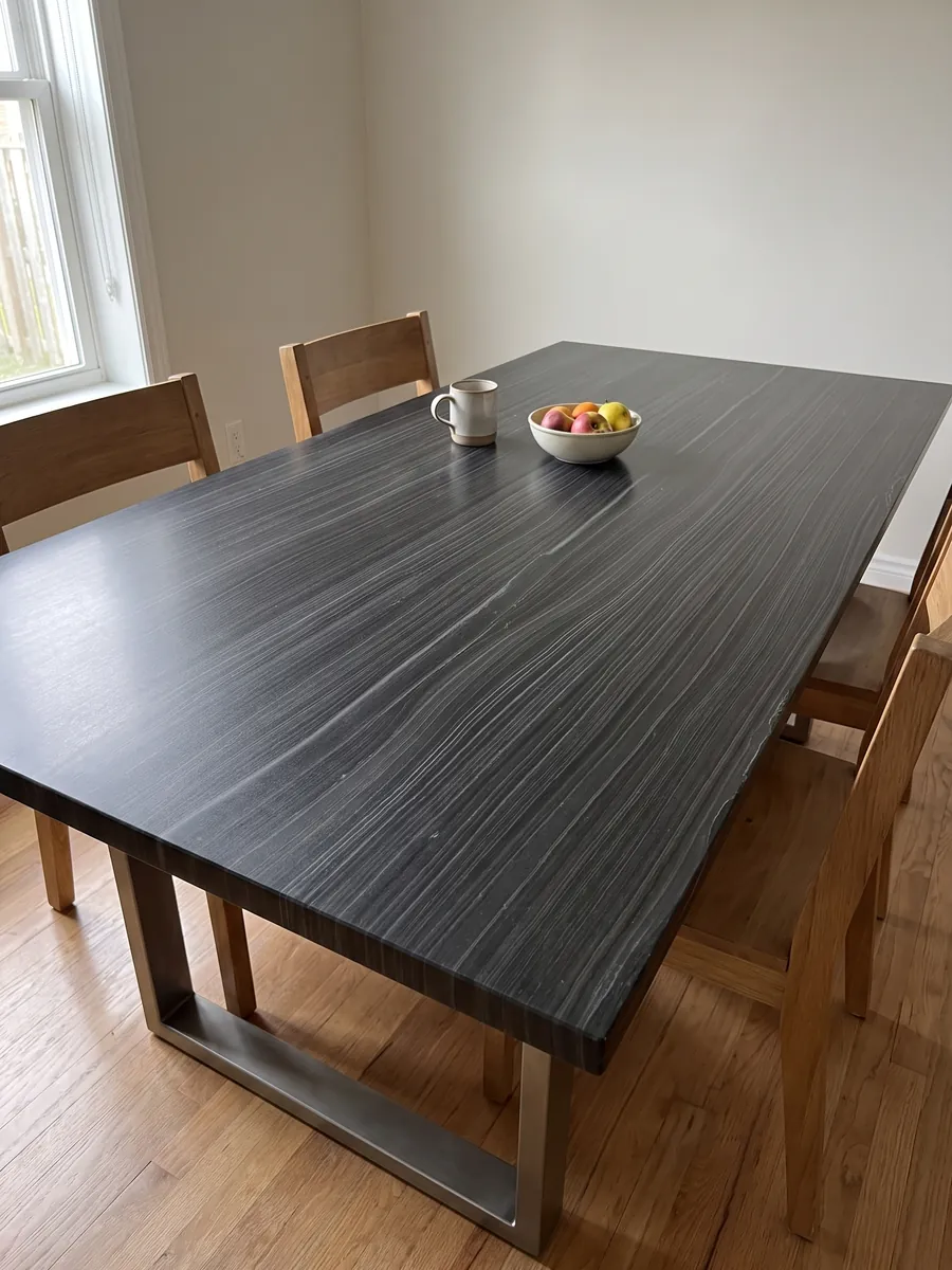 Dining table with a Nero Pagoda marble top on a steel base: black with fine horizontal, parallel gray lines, almost like wood